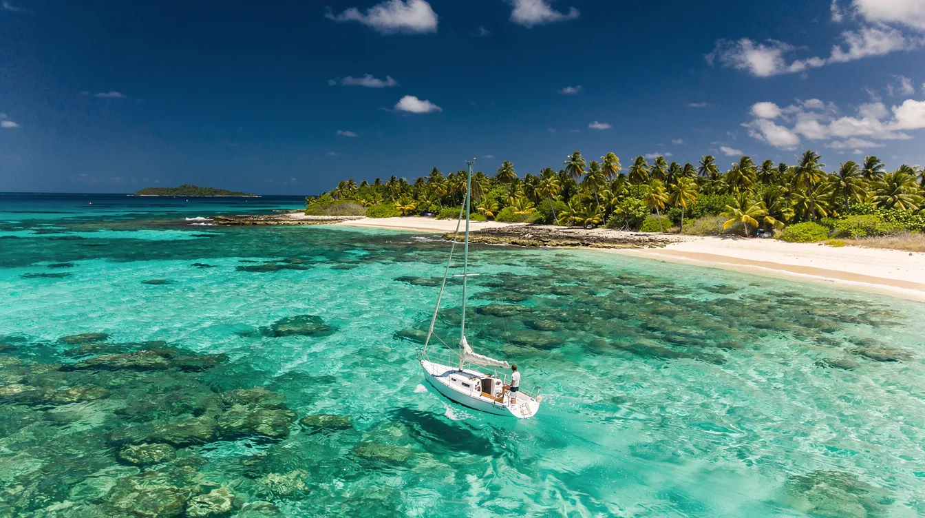 Um iate elegante navega em águas azul-turquesa, cercado por ilhas tropicais no Caribe colombiano, criando uma imagem paradisíaca que evoca o turismo em Cartagena e Santa Marta. O cenário é perfeito para aventuras em família, com praias deslumbrantes e a tranquilidade da natureza ao redor.